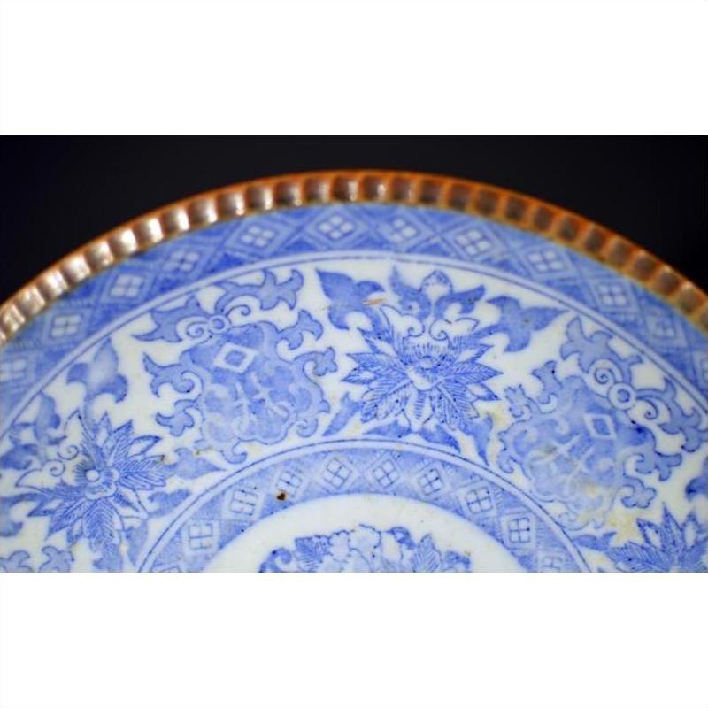 Close-up of blue and white ceramic Japanese Igezara plate with floral patterns and ridged brown glazed edge.