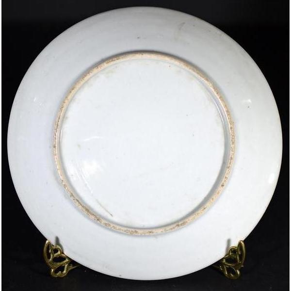 Close-up of the back of an antique Japanese Igezara transferware plate on a gold stand against a black background.