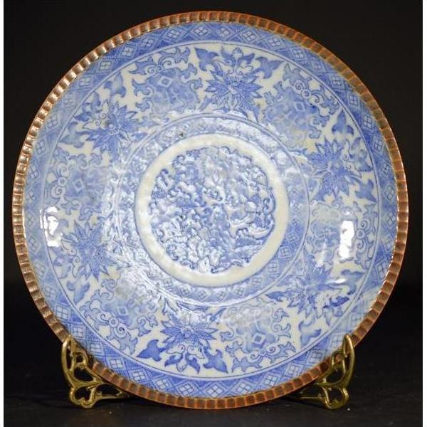 Blue and brown porcelain Igezara transferware plate with ornate floral pattern, displayed on gold stand.