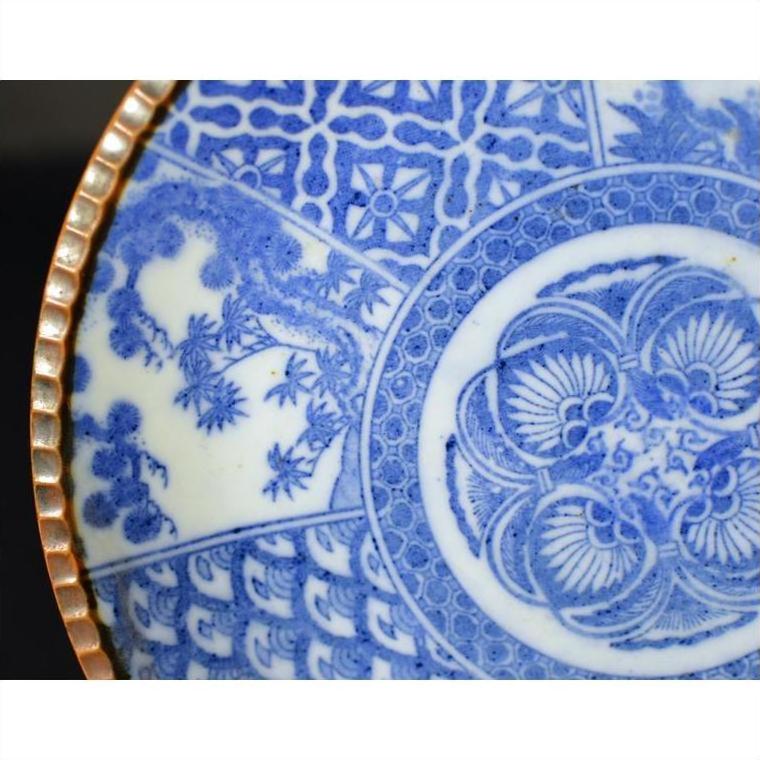 Close-up of blue and white porcelain Igezara plate with floral and geometric patterns, gold trim, antique Japanese style.