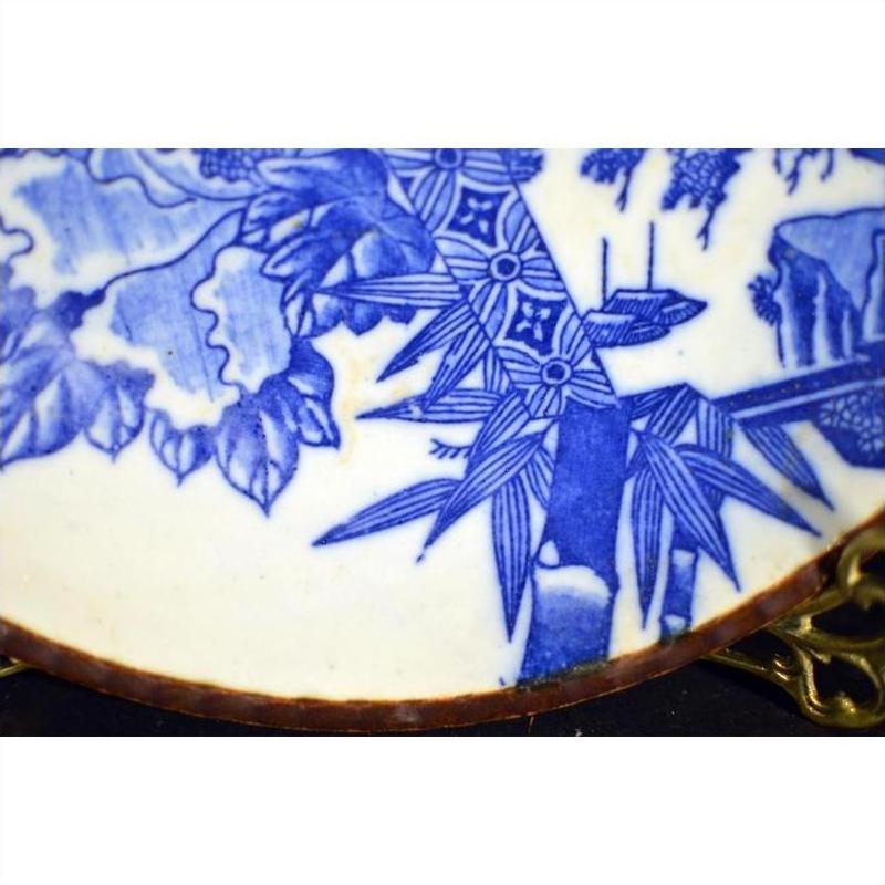 Close-up of blue and white porcelain Japanese Igezara transferware plate on brass stand.