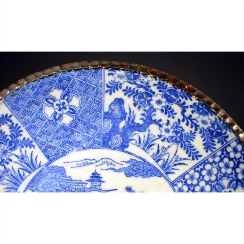 Blue and white porcelain Igezara plate with floral and geometric designs, metal-trimmed edge, close-up view.