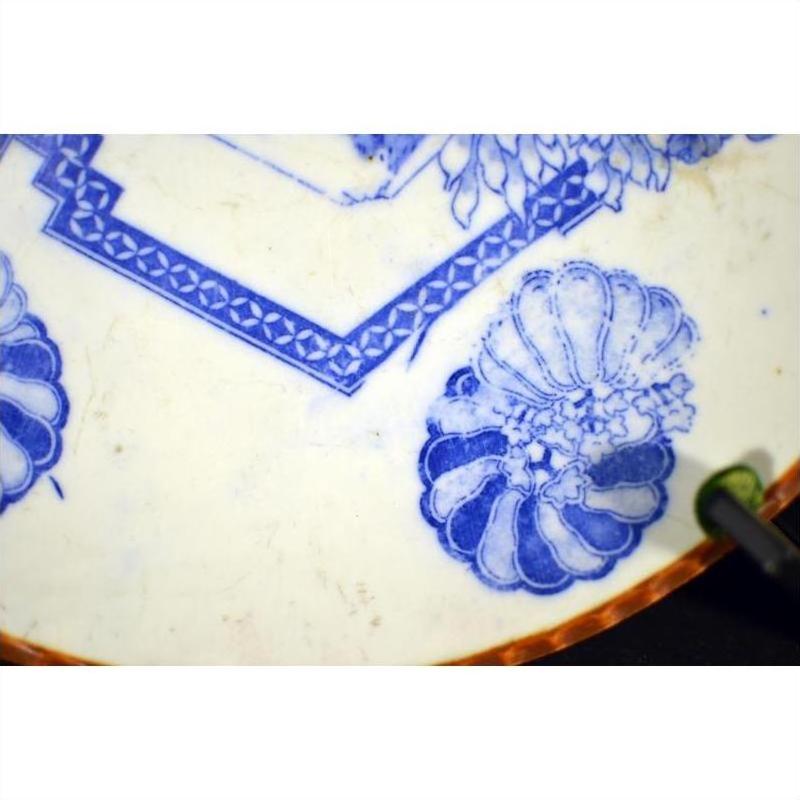 Blue and white porcelain Igezara plate with brown rim, featuring floral and geometric designs, close-up.