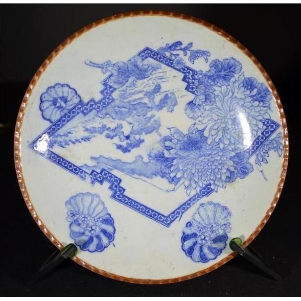 Blue and white porcelain Igezara plate with floral design and copper rim, on display stand.