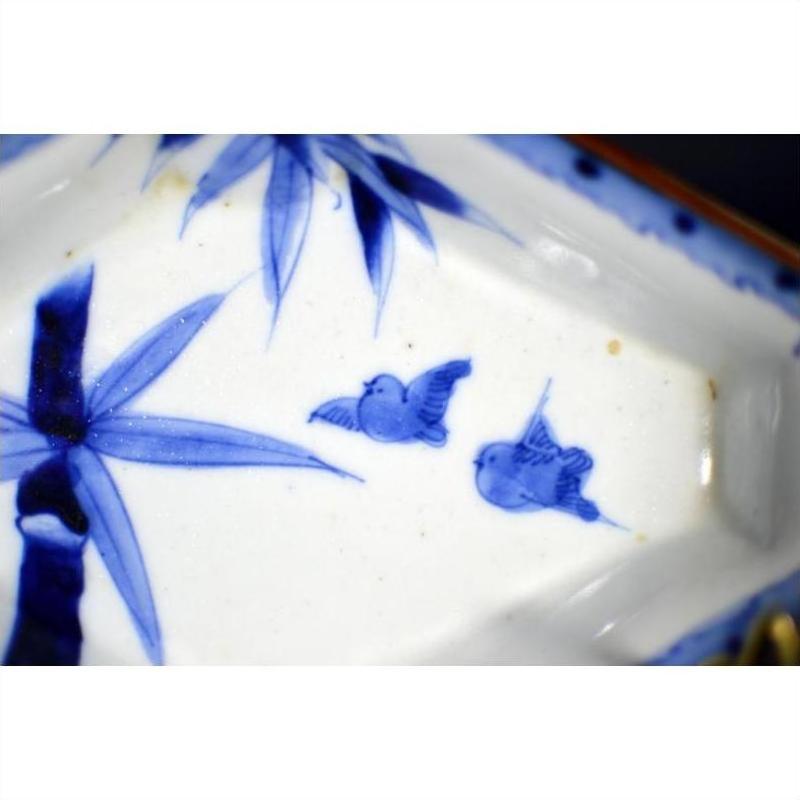Blue and white porcelain Imari bowl with hand painted birds and bamboo leaves, close-up view.