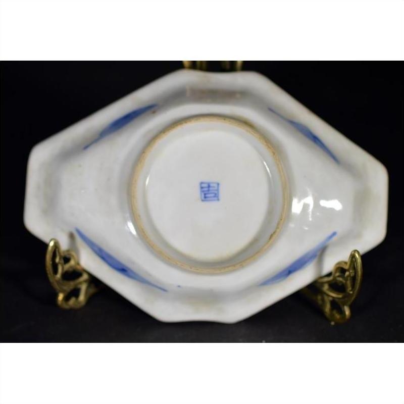 Bottom view of blue and white porcelain Imari bowl with hand painted accents and seal mark, displayed on gold stand.