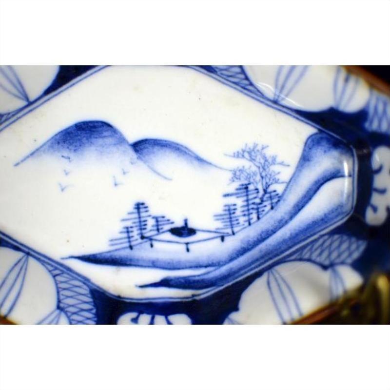 Blue and white porcelain Imari bowl with hand painted landscape of mountains, trees, and a bridge.
