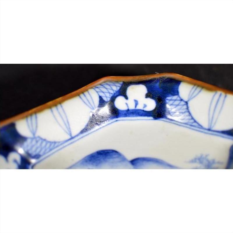 Blue and white porcelain Imari bowl with hand-painted pattern and brown-edged rim, on display.