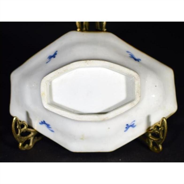 Close-up of blue and white porcelain Imari bowl with hand painted designs on decorative brass stand, blue markings visible.