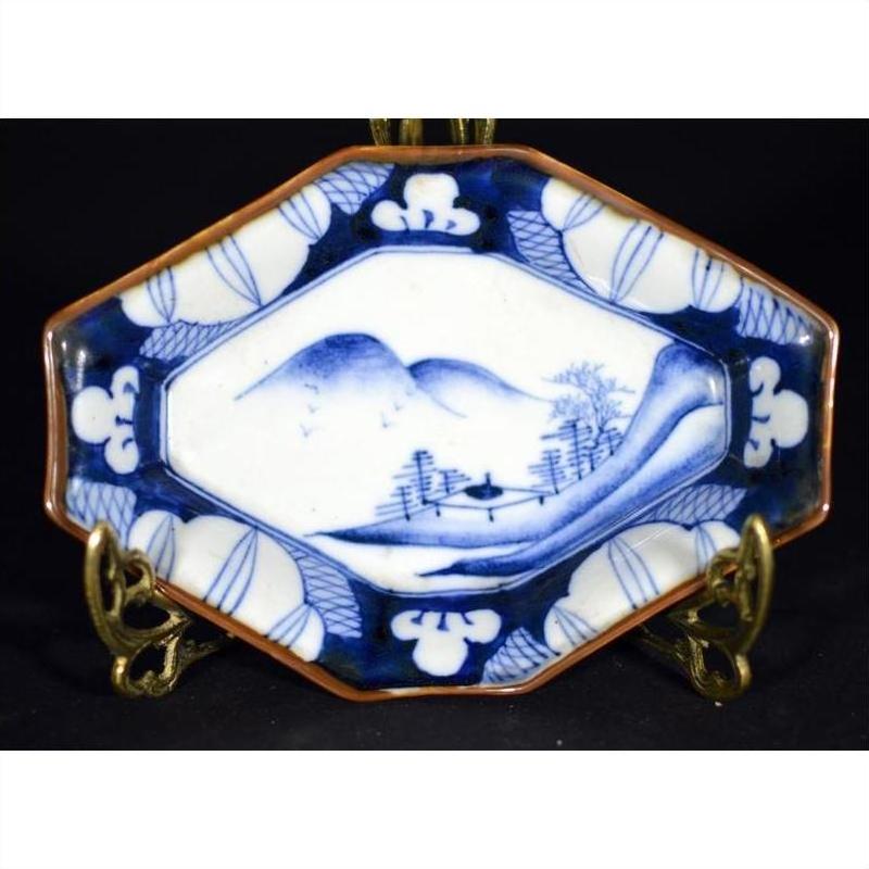 Blue and white porcelain Imari bowl with hand painted landscape, mountains, trees, and decorative border.