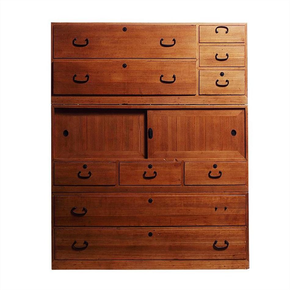 Brown Japanese kiri wood chest with black metal handles and sliding center doors, studio background.