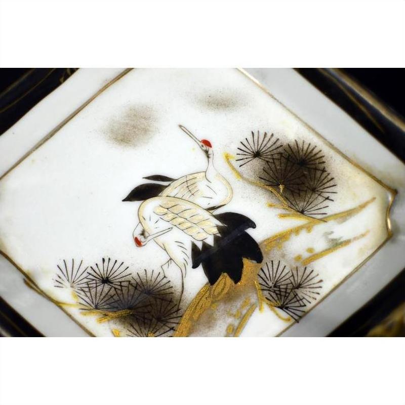 White porcelain Kutani dish with two white cranes, red crowns, and pine branches on a white background.