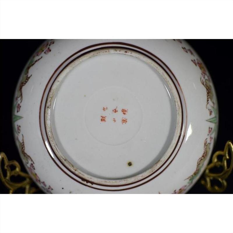 Close-up of the base of an antique Japanese Kutani porcelain plate with red characters and a floral rim border.