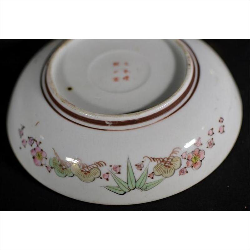 White porcelain plate with pink flowers and green leaves, shown upside down.