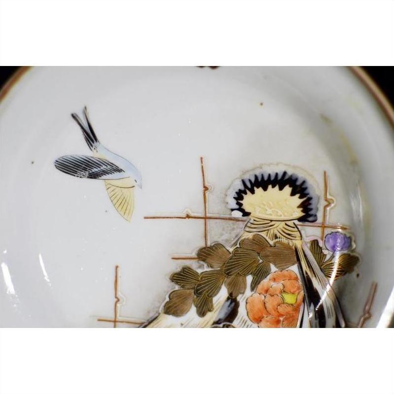 White porcelain Kutani plate with hand-painted bird, flowers, and gold-accented branches, close-up.