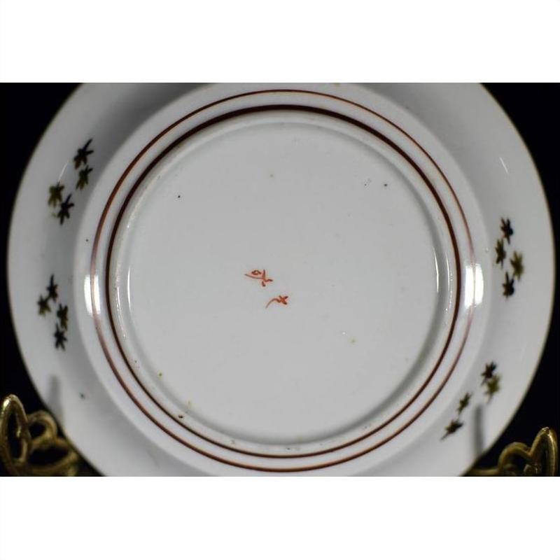 White porcelain plate underside with red circular lines and a small central red maker’s mark, close-up view.
