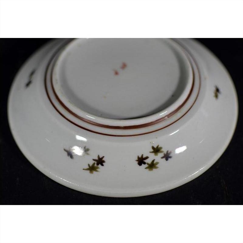 White porcelain plate with red lines and small colored floral motifs on base, antique style.