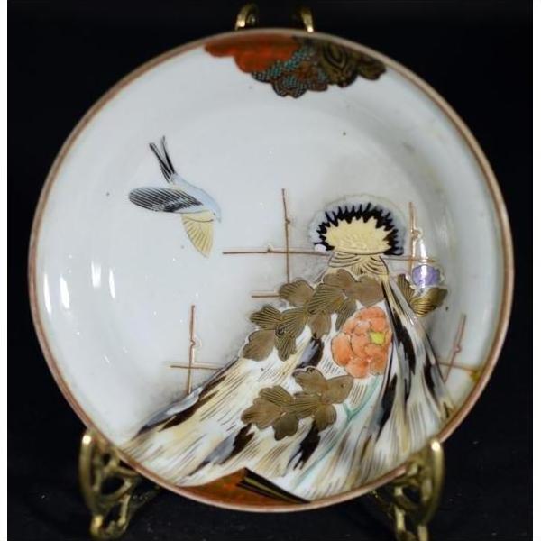 Close-up of a multicolor hand painted Japanese Kutani porcelain plate with birds, gold leaves, and floral design on stand.
