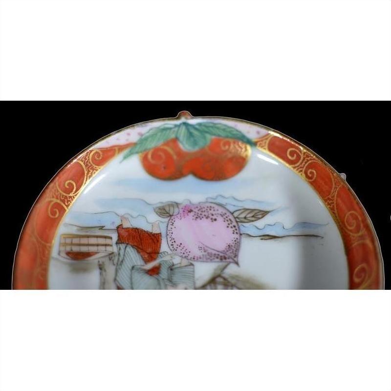 Close-up of antique Japanese Satsuma ceramic plate with red and gold border, hand painted fruit and leaf design.
