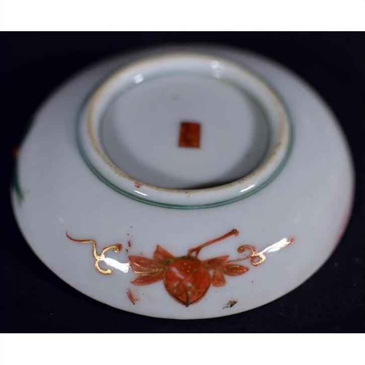 Red and gold porcelain plate underside with hand-painted floral patterns and a red mark, close-up.