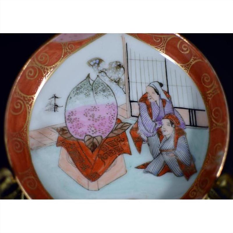 Close-up of an antique Japanese Satsuma porcelain plate with two figures and a large peach, hand painted, multicolor.