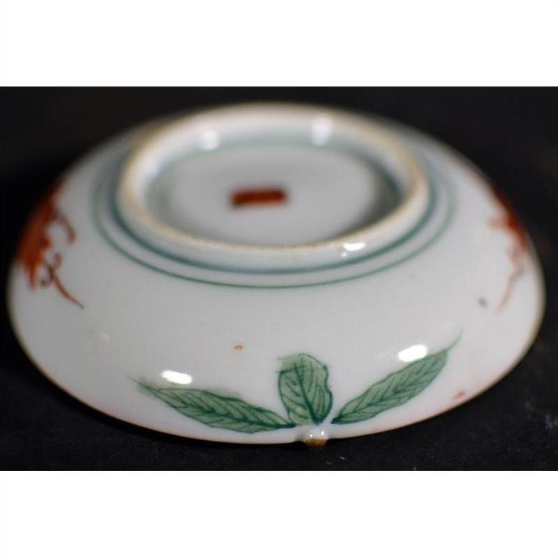 Close-up of the base of an antique Japanese Satsuma plate with green leaf designs and a red central mark.