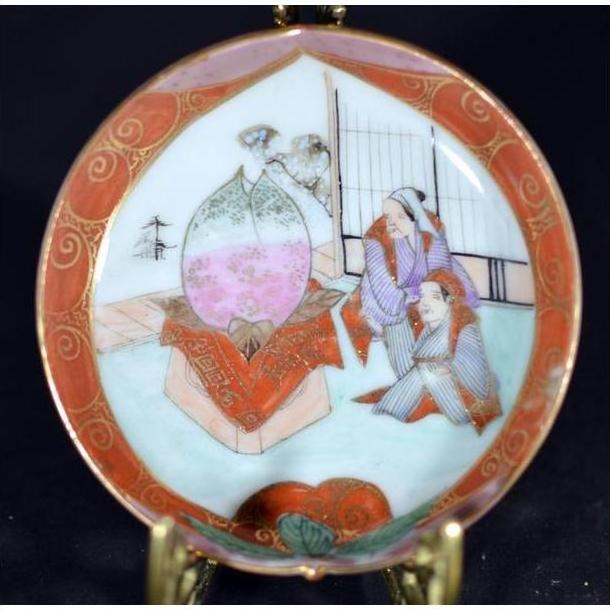 Close-up of antique Japanese Satsuma porcelain plate with hand painted figures in traditional dress and large indoor vase.