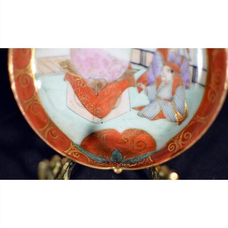 Close-up of an antique Japanese Satsuma porcelain plate with intricate hand-painted scene and seated figure.