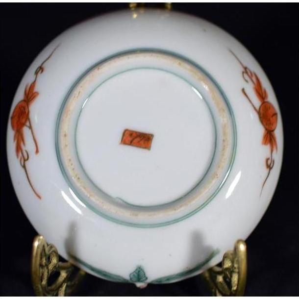 Close-up of the underside of an antique Japanese Satsuma porcelain plate with red-green designs and red rectangular mark.