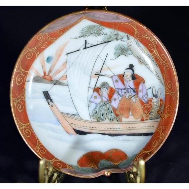 Close-up of a multicolor ceramic Satsuma plate with two figures on a sailboat, trees, and waves hand painted.