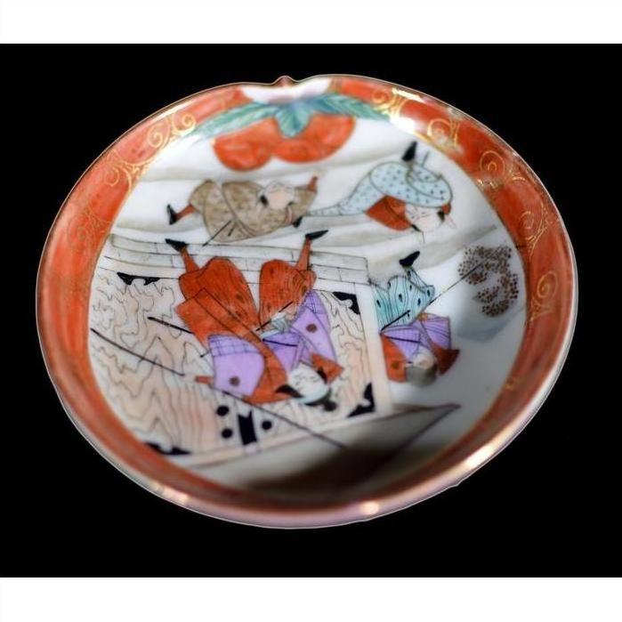 Close-up of colorful hand-painted figures and patterns on a black porcelain antique Japanese Satsuma plate.