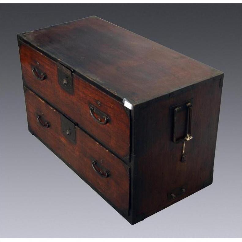Brown wood Japanese Tansu chest with metal handles, side lock, and two large drawers against gray background.