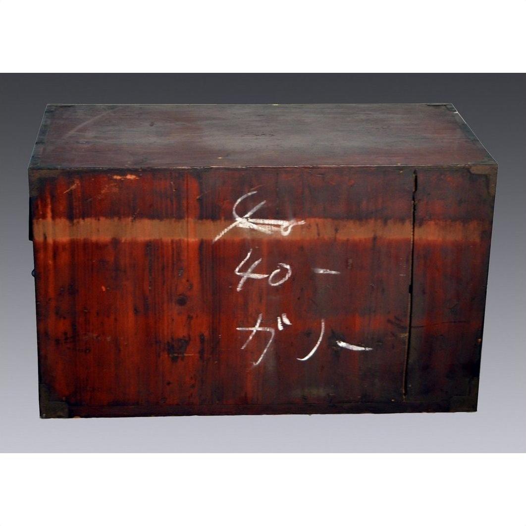 Close-up of antique red-toned wooden Japanese Tansu with worn finish and white Japanese chalk writing on the front.
