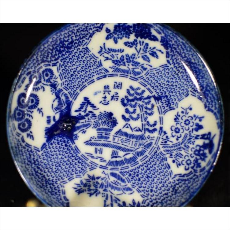 White porcelain Japanese transferware plate with blue floral and landscape patterns, antique style, close-up.