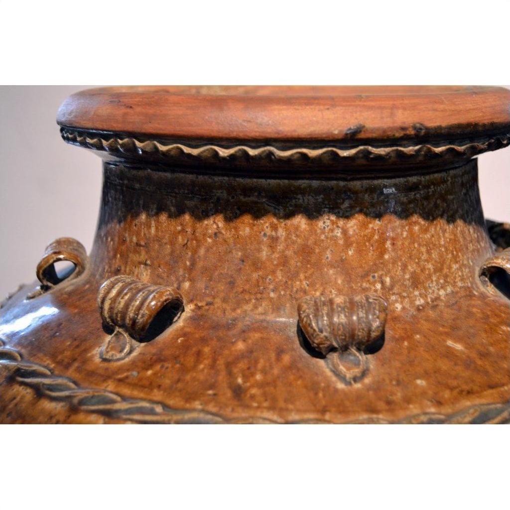 Close-up of brown ceramic Antique Martaban water jar neck and rim with decorative loops and organic details.
