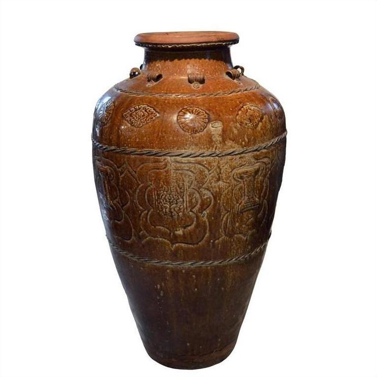 Brown ceramic antique Martaban water jar with carved patterns and slightly flared rim on white background.