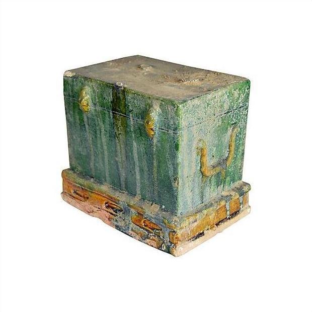 Close-up of a small, weathered green and brown antique miniature Chinese treasure chest on matching base.