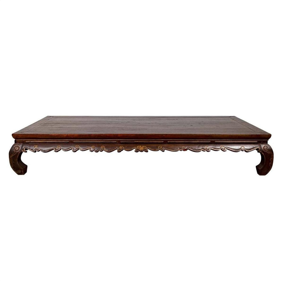 Brown wooden low table with ornate carved legs, inspired by antique Ming Dynasty Kang Opium Bed design, indoor setting.