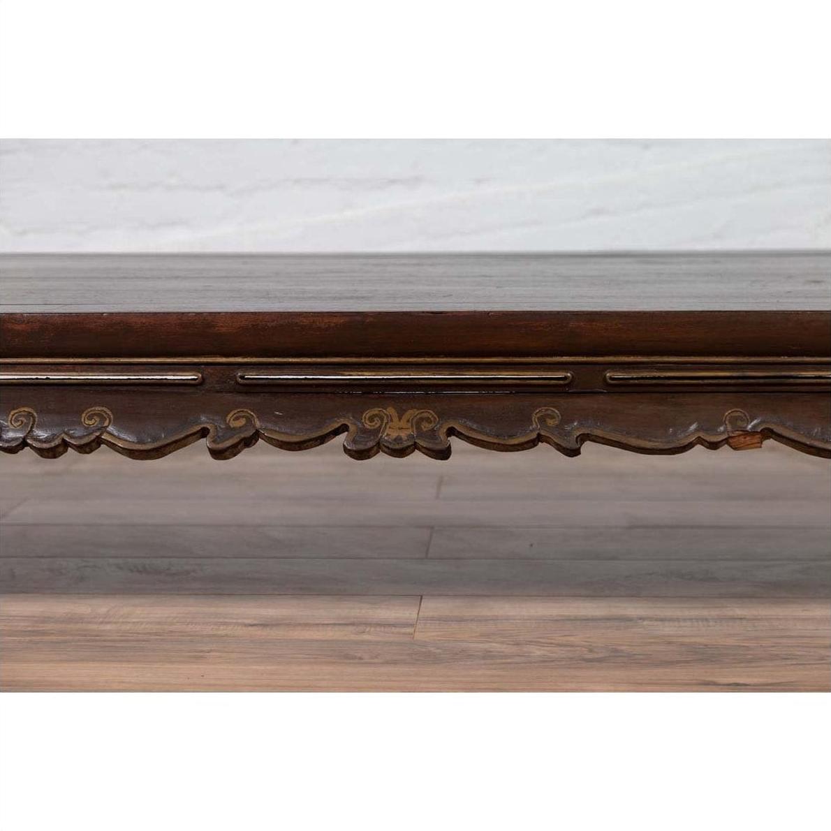 Close-up of a dark wood hand-carved edge on an antique Ming Dynasty style opium bed near a light wall and floor.