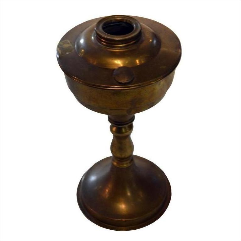 Brass oil lamp with round body, slender stem, and flared base on white background.