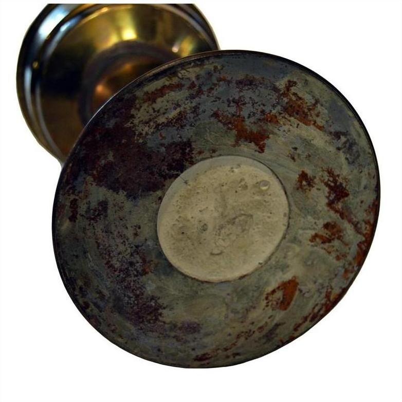 Close-up of brass antique oil lamp base with visible rust and tarnish on the underside.