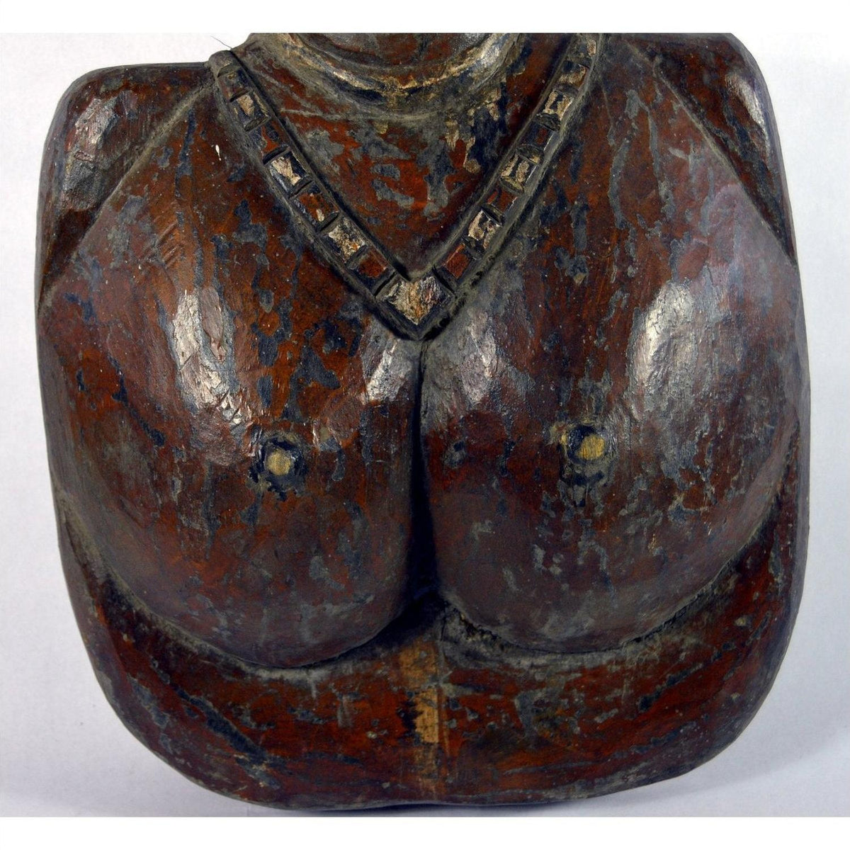 Brown wooden Sumatra fertility mask bust with necklace, prominent breasts, and worn paint, close-up view.