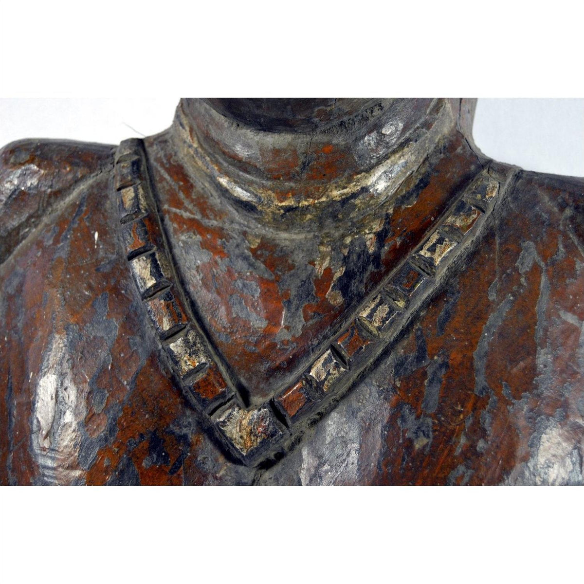 Close-up of antique Sumatra fertility mask, dark-toned material, with square-patterned necklace and shoulders visible.