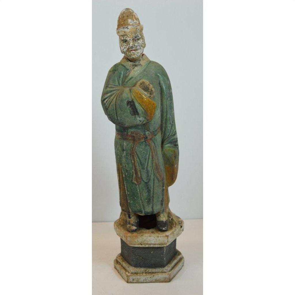 Green terracotta court figure statue with hat on hexagonal base, close-up view.