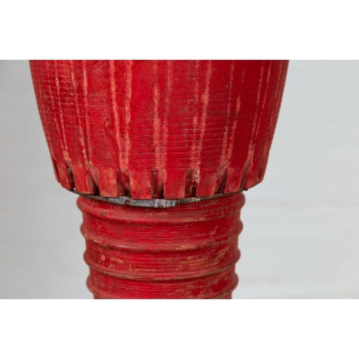 Close-up of red ribbed wooden leg from an antique Thai ceremonial drum with round base.