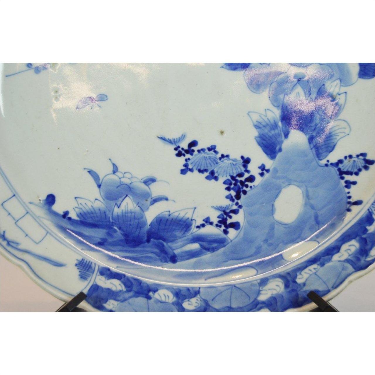 Close-up of blue and white porcelain plate with floral designs on a decorative stand.