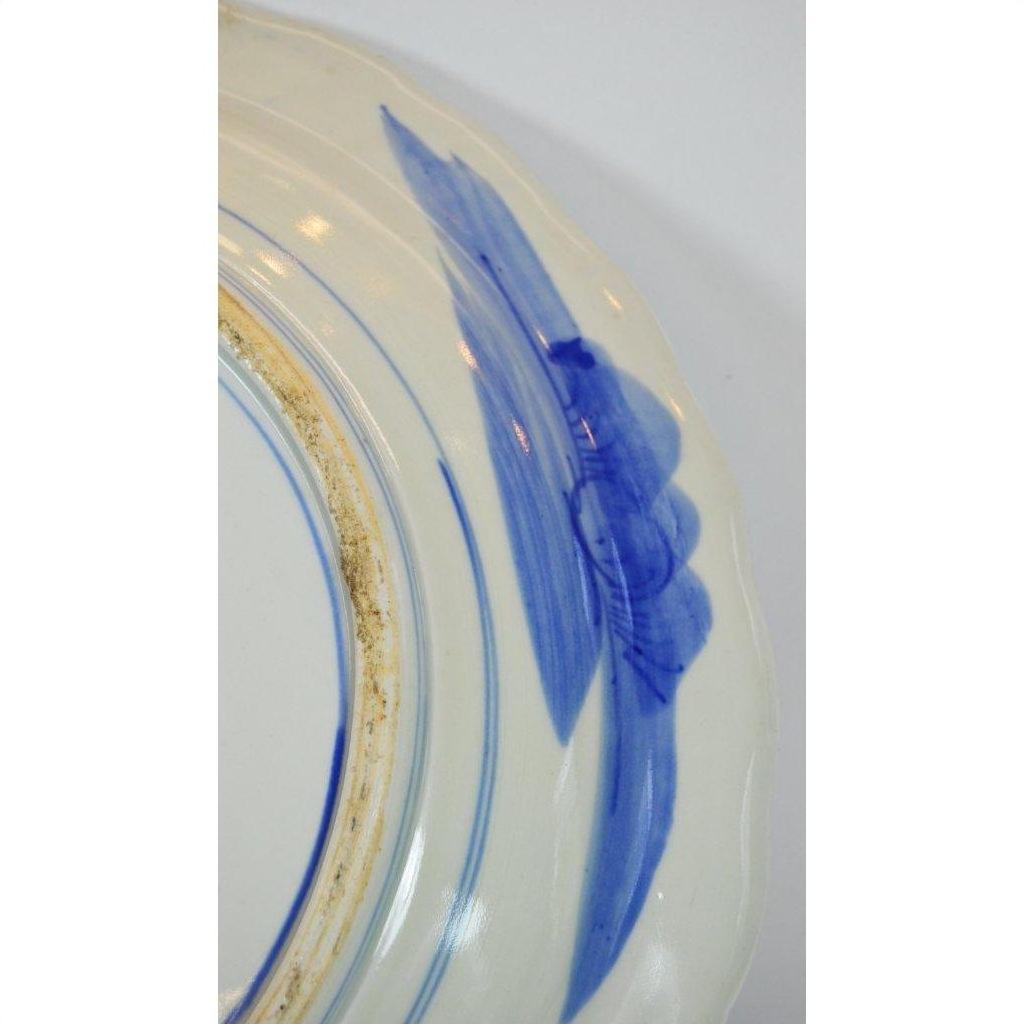Close-up of white ceramic plate with blue brushstrokes and concentric blue edge lines.