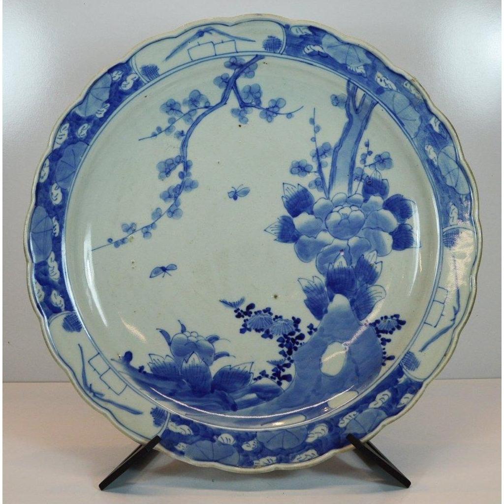 Blue and white porcelain plate with hand painted floral and bird design, displayed on a black stand.