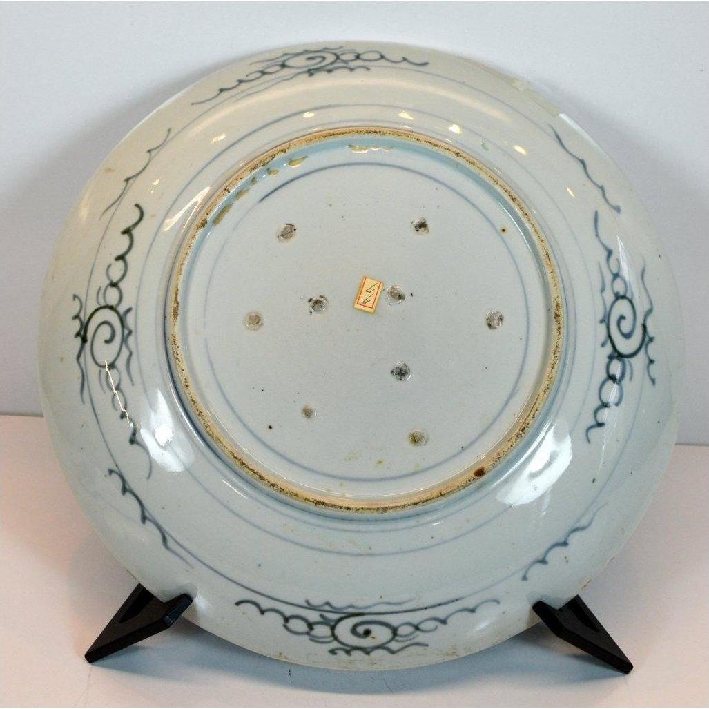 Close-up of the white porcelain ARITA MEIJI hand-painted plate underside with blue swirls, on a black stand.