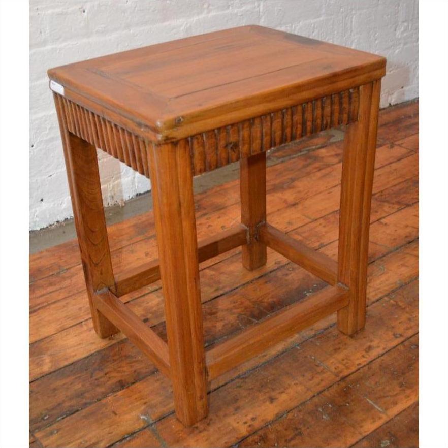 Brown wood Art Deco stool with carved details on wooden floor, vintage Shanghai style.